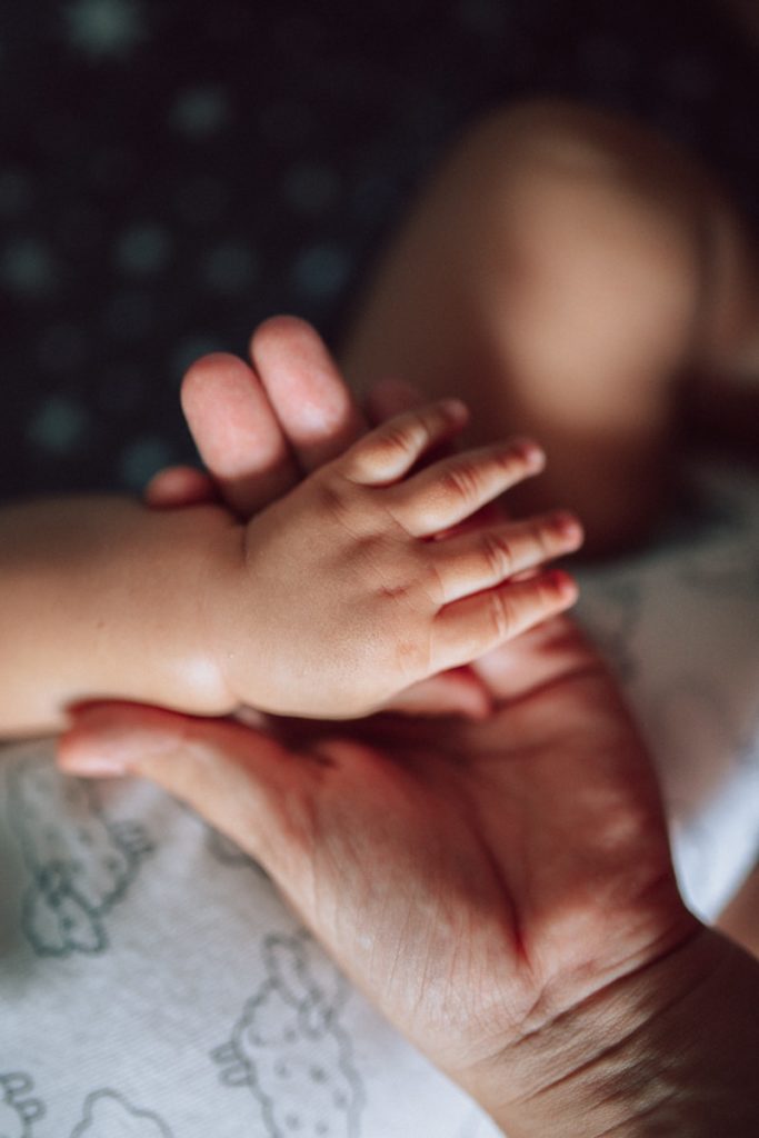 Photo by Izabelly Marques a baby's hand holding a baby's foot